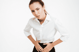 Portrait of a young businesswoman with menstrual pain and looking at camera over white background