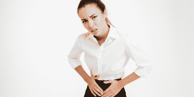 Portrait of a young businesswoman with menstrual pain and looking at camera over white background