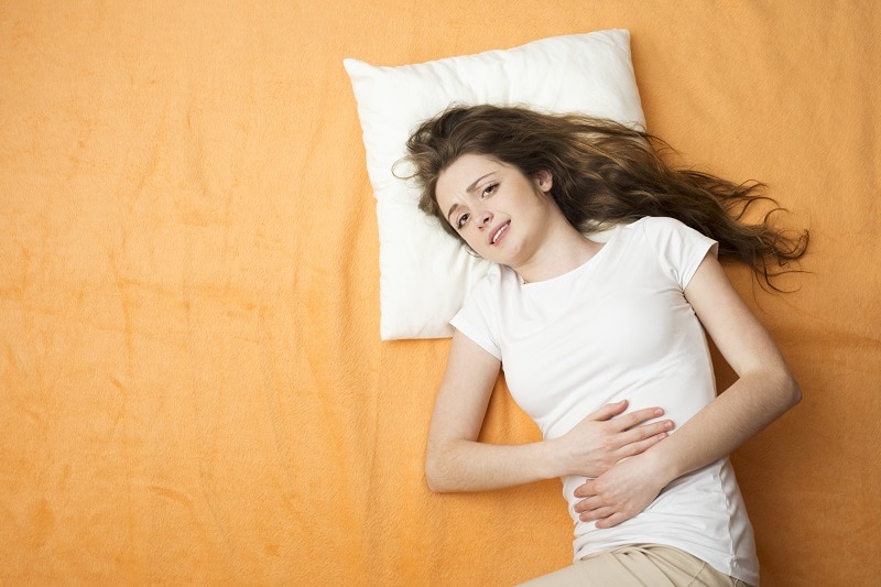 Sick woman with menstruation is lying on the bed.